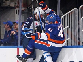 Adam Lowry (17) of the Winnipeg Jets checks Robert Bortuzzo (41) of the New York Islanders during the second period at UBS Arena on March 23, 2024 in Elmont, N.Y.