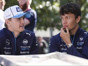 Williams driver Logan Sargeant, left, of the US and teammate Alexander Albon of Thailand react as they sit outside their team garage ahead of the Australian Formula One Grand Prix at Albert Park, Melbourne, Australia, Thursday.