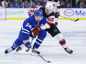 Toronto Maple Leafs centre Auston Matthews (34) and New Jersey Devils left-winger Erik Haula (56) battle for the puck during first period NHL hockey action in Toronto on Tuesday, March 26, 2024.