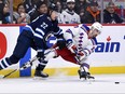 New York Rangers' Chris Kreider (20) passes the puck as he is checked by Winnipeg Jets' Mason Appleton (22) earlier this season.