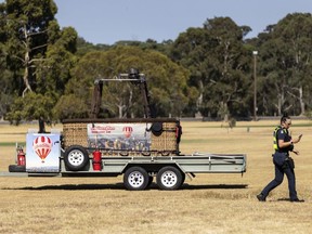 A police officer walks past a trailer with a hot-air balloon basket on it after the discovery of a man's body at Yarra Bend Park in Melbourne, Monday, March 18, 2024. A man has fallen to his death from a hot-air balloon as it passed over suburban Melbourne, Australia's second largest city.