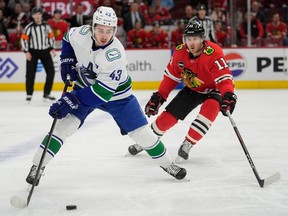 Chicago Blackhawks right wing Taylor Raddysh, right, chases after Vancouver Canucks defenceman Quinn Hughes and the puck during the first period of a hockey game, Tuesday, Feb. 13, 2024, in Chicago.
