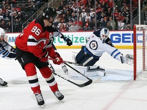 Laurent Brossoit of the Winnipeg Jets makes the second period save on Jack Hughes of the New Jersey Devils at the Prudential Center on March 21, 2024 in Newark, New Jersey.