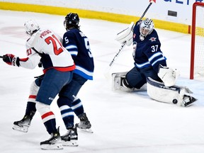 Winnipeg Jets goaltender Connor Hellebuyck (37) makes a save on a Washington Capitals shot as Brenden Dillon (5) defends against Aliaksei Protas (21) during the first period of NHL action in Winnipeg on Monday March 11, 2024.