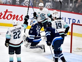 Seattle Kraken's Justin Schultz (4) celebrates his goal against Winnipeg Jets goaltender Connor Hellebuyck (37) with Oliver Bjorkstrand (22) and Jared McCann (19) during the first period of NHL action in Winnipeg on Tuesday March 5, 2024.