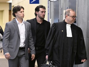 Former Victoriaville Tigres junior major hockey league players Nicolas Daigle, left, and Massimo Siciliano, follow defence lawyer Michel Lebrun, right, out of the courtroom on Wednesday, Oct. 11, 2023, in Quebec City. A Quebec judge will render a sentence in July for two former Quebec major junior hockey players who pleaded guilty to sexually assaulting a minor in June 2021 as their team celebrated a championship at a hotel.