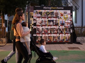 An Israeli couple with children walks past portraits of Israeli hostages held since October 7 by the Palestinian Hamas movement, in Tel Aviv on March 2, 2024.