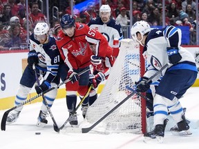 Washington Capitals defenceman Trevor van Riemsdyk (57) tries to maneuver the puck past Winnipeg Jets left wing Kyle Connor (81) in the first period of an NHL hockey game, Sunday, March 24, 2024, in Washington. Jets defenceman Neal Pionk, right, looks on.