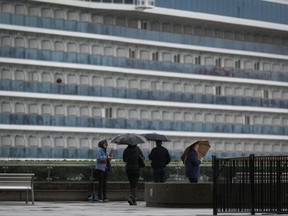 People use umbrellas to shield themselves from the rain as the Princess Cruises cruise ship Majestic Princess is seen docked at port, in Vancouver, B.C., Monday, Sept. 25, 2023.