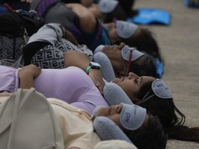 Equipped with mats, sleeping masks and travel pillows, people lie sprawled out at the base of the iconic Monument to the Revolution to take a nap, in Mexico City, Friday, March 15, 2024. Dubbed the "mass siesta," the event was in commemoration of World Sleep Day.