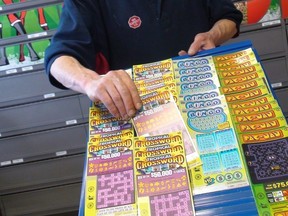 In this file photo, a convenience store employee removes a scratch-and-win lottery ticket on Sunday, Nov. 21, 2010 in Ottawa.