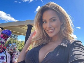 Selfie of smiling Paige Spiranac next to golf cart.