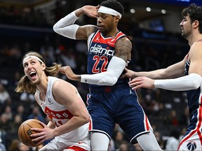 Toronto Raptors forward Kelly Olynyk, left, works against Washington Wizards forward Richaun Holmes (22) for a shot with Wizards forward Deni Avdija, right, moving in during the first half of an NBA basketball game Saturday, March 23, 2024, in Washington.