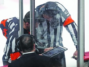 NHL officials take time out from a Flames-Canadiens game to review a play on a tablet.