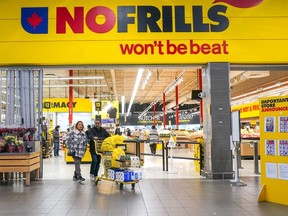 A customer pushes a shopping cart full of groceries from a NoFrills grocery store, in Toronto, on Thursday, Nov. 23, 2023.