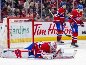 Montreal Canadiens' Cayden Primeau lays on the ice after giving up a goal to Tampa Bay Lightning's Steven Stamkos during the second period of a National Hockey League game in Montreal Thursday April 4, 2024. Defencemen Arber Xhekaj and Jordan Harris, right, skate away at rear.