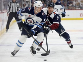 Sean Monahan of the Winnipeg Jets battles with Zach Parise of the Colorado Avalanche in the first period at Ball Arena on April 13, 2024 in Denver, Colo.