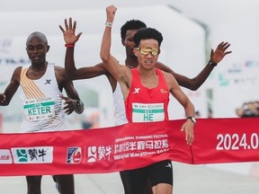 Chinese distance runner He Jie crosses the finish line of the Beijing Half Marathon.