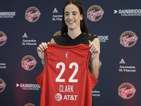 Caitlin Clark of the Indiana Fever holds up her jersey.