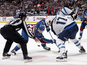Winnipeg Jets captain Adam Lowry (right) contests a faceoff against Nathan MacKinnon of the Colorado Avalanche during the second period of Game Four of the first-round playoff series between the team on April 28, 2024 at Ball Arena in Denver.