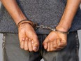 Close-up. Arrested man handcuffed hands at the back. Prisoner or arrested terrorist, close-up of hands in handcuffs, selective focus.