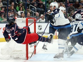 Johnny Gaudreau (13) of the Columbus Blue Jackets loses his footing after tripping over the stick of Neal Pionk (4) of the Winnipeg Jets during the second period of the game at Nationwide Arena on March 17, 2024 in Columbus, Ohio.