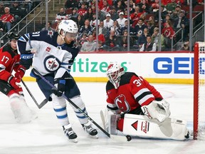 Jake Allen (34) of the New Jersey Devils makes the first period save on Kyle Connor (81) of the Winnipeg Jets at Prudential Center on March 21, 2024 in Newark, N.J.