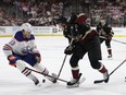 Josh Doan #91 of the Arizona Coyotes skates with the puck against Mattias Janmark #13 of the Edmonton Oilers during the second period of the NHL game at Mullett Arena on April 17, 2024 in Tempe, Arizona.