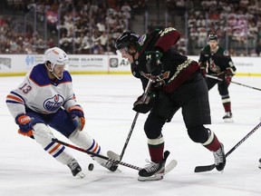 Josh Doan #91 of the Arizona Coyotes skates with the puck against Mattias Janmark #13 of the Edmonton Oilers during the second period of the NHL game at Mullett Arena on April 17, 2024 in Tempe, Arizona.