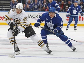 Hampus Lindholm #27 of the Boston Bruins skates with the puck against Max Domi #11 of the Toronto Maple Leafs in Game Three of the First Round of the 2024 Stanley Cup Playoffs at Scotiabank Arena on April 24, 2024 in Toronto.