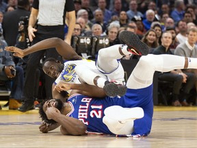 Golden State Warriors forward Draymond Green (23) falls over Philadelphia 76ers centre Joel Embiid (21) on an offensive foul by Embiid during the first half of an NBA basketball game, Tuesday, Jan. 30, 2024, in San Francisco.