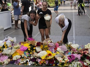 Three women place flowers as a tribute near a crime scene at Bondi Junction in Sydney, Sunday, April 14, 2024.