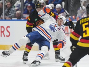 Edmonton Oilers forward Leon Draisaitl (27) is hauled down by the Vancouver Canucks' Dakota Joshua in Vancouver on Nov. 6, 2023.