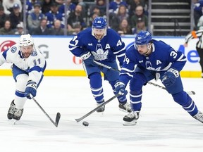 Maple Leafs' Auston Matthews, right, and Tampa Bay Lightning's Luke Glendening reach for the puck during the first period in Toronto, on Wednesday, April 3, 2024.