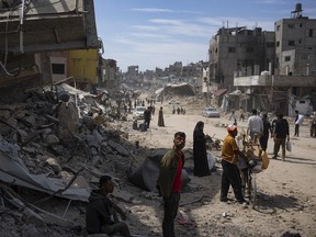 Palestinians walk through the destruction in the wake of an Israeli air and ground offensive in Khan Younis, southern Gaza Strip, Monday, April 8, 2024. Israel says it has withdrawn its last ground troops from the city, ending a four-month operation.