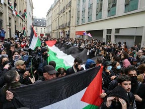 Protesters brandish a giant Palestinian flag as they gather in support of Palestinians outside a building of the Institute of Political Studies (Sciences Po Paris) occupied by students, in Paris on April 26, 2024.