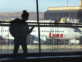An airline passenger passes by the new Lynx Air Boeing 737 on the tarmac at the Calgary International Airport in Calgary on Thursday, April 7, 2022.