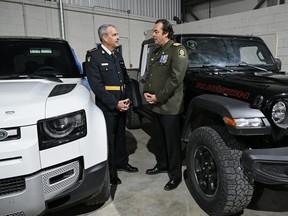 Ontario Provincial Police Deputy Commissioner Marty Kearns (L) talks to Deputy Chief Benoit Dube, of the Surete du Quebec, next to two recovered stolen vehicles during a news conference in Montreal on Wednesday, April 3, 2024.