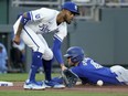 George Springer of the Toronto Blue Jays beats the tag by Kansas City Royals third baseman Maikel Garcia to advance to third on a single by Bo Bichette during the third inning of a baseball game April 23, 2024, in Kansas City, Mo.