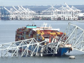 In this aerial image, the steel frame of the Francis Scott Key Bridge sits on top of a container ship after the bridge collapsed, Baltimore, Maryland, on March 26, 2024.