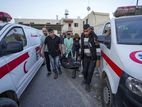 Palestinians carry the body of a World Central Kitchen worker at Al Aqsa hospital in Deir al-Balah, Gaza Strip, Tuesday, April 2, 2024. A Canadian-American citizen is among the seven aid workers who were killed by an apparent Israeli airstrike in Gaza.