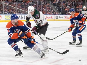 Arizona Coyotes' Jan Jenik (73) and Edmonton Oilers' Mattias Ekholm (14) battle for the puck during first period NHL action in Edmonton on Friday April 12, 2024.