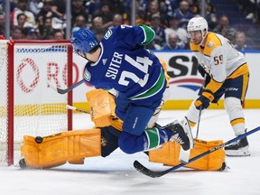 Vancouver Canucks' Pius Suter, front, is stopped by Nashville Predators goalie Juuse Saros, back, as Roman Josi, back right, watches during the first period in Game 2 of an NHL hockey Stanley Cup first-round playoff series, in Vancouver, on Tuesday, April 23, 2024.