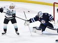 Winnipeg Jets goaltender Connor Hellebuyck (37) makes a save as Seattle Kraken's Jaden Schwartz (17) deflects the puck during the first period of NHL action in Winnipeg on Tuesday April 16, 2024.