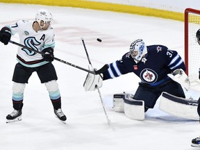 Winnipeg Jets goaltender Connor Hellebuyck (37) makes a save as Seattle Kraken's Jaden Schwartz (17) deflects the puck during the first period of NHL action in Winnipeg on Tuesday April 16, 2024.