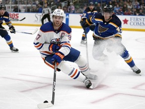 Edmonton Oilers' Connor McDavid (97) handles the puck as St. Louis Blues' Torey Krug (47) and Jake Neighbours (63) defend during the third period of an NHL hockey game Monday, April 1, 2024, in St. Louis.