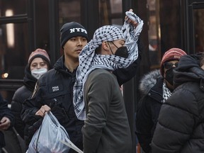 A police officer removes a keffiyeh scarf from a protester arrested after blocking the Brooklyn Bridge during a pro-Palestinian demonstration demanding ceasefire on the Israel-Palestinian conflict in New York City, Jan. 8, 2024.