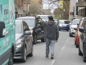 A homeless native man panhandles between cars stopped at a red light in Montreal on Wednesday, May 4, 2022. An Ontario court has struck down sections of the province's panhandling law as unconstitutional.