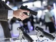 An attendee holds a pistol at the booth of an exhibitor at the CANSEC trade show in Ottawa on Wednesday, June 1, 2022.