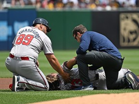Ronald Acuña Jr. of the Atlanta Braves is attended to by a trainer and third base coach Matt Tuiasosopo (89) after falling to the ground with an apparent injury in the first inning during the game against the Pittsburgh Pirates at PNC Park on Sunday, May 26, 2024, in Pittsburgh, Pa.
